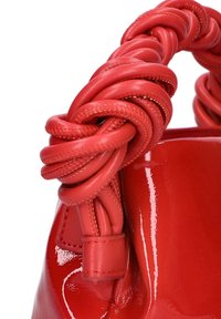 Rode lakleren handtas met een dikke, gevlochten rode leren hendel. Het oppervlak is glanzend, met een soepele textuur en subtiele stikdetails.