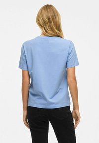 Kortärmad ljusblå t-shirt med rund halsringning och avslappnad passform, tillverkad av mjukt bomullsmaterial, sedd bakifrån.