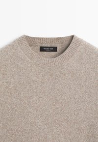 Pull en laine beige à col rond avec col côtelé, étiqueté "Massimo Dutti", fabriqué en Italie, présenté sur fond blanc.