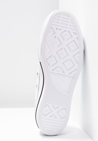 Suela de zapatilla de goma blanca con patrón de huella geométrica, línea de acento negra y logotipo de la marca. Plana, sin elevación.