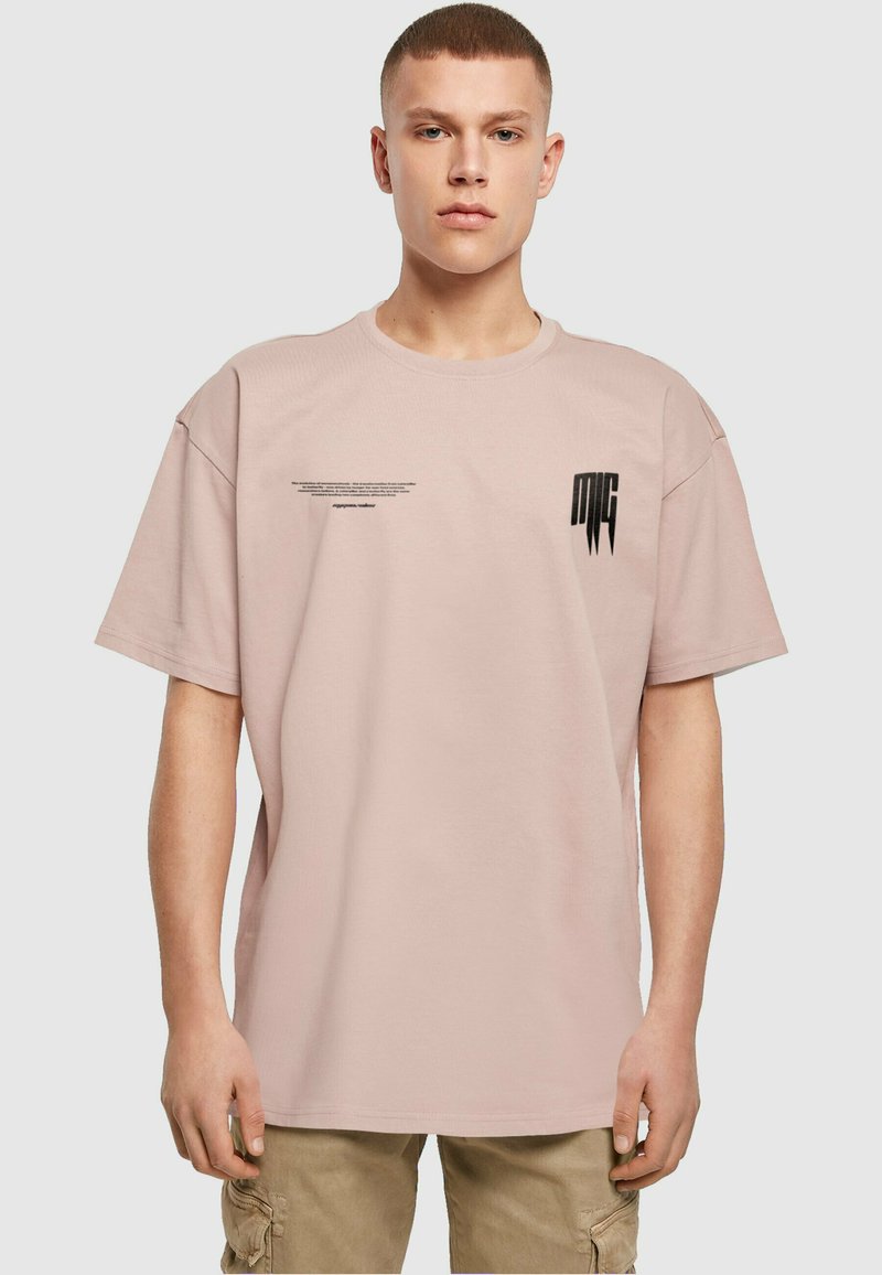 Lyserød bomulds T-shirt med en afslappet pasform. Har sort grafisk tekst og logoer på fronten. Korte ærmer og rund halsudskæring.