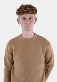 Lys brun ribbestrikket genser med rund hals og lange ermer, med teksturert stoff og en tettsittende design.