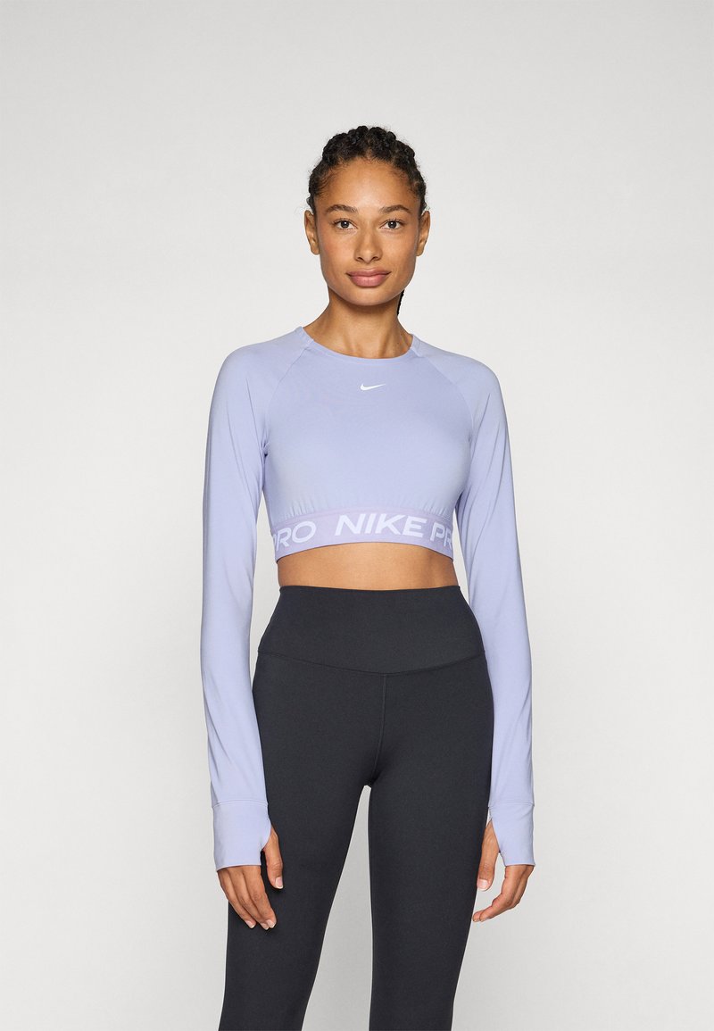 Lichtpaarse langmouwen cropped top met een ronde halslijn en het "NIKE PRO"-logo op de zoom, gecombineerd met zwart high-waisted leggings.