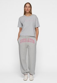 Camiseta gris corta con letras rosas "10 DÍAS" y pantalones de chándal grises a juego que presentan la misma letra rosa en la cintura.