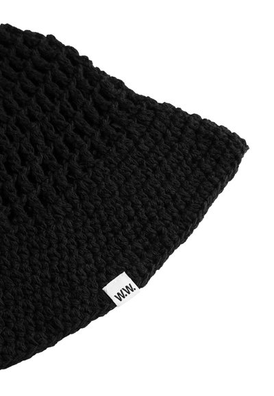 Μαύρο πλεκτό ύφασμα με μια λευκή ορθογώνια ετικέτα με την επιγραφή "W.W." σε μια γωνία, εμφανιζόμενο σε λευκό φόντο.