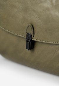 Borsa in pelle verde oliva con texture liscia, chiusura in metallo nero e dettagli di cucitura a contrasto lungo il bordo.