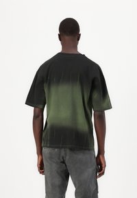 Czarny i zielony gradientowy t-shirt z krótkim rękawem wykonany z bawełny, o luźnym kroju i okrągłym dekolcie, z przeszywanymi detalami.