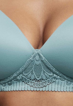 Reggiseno azzurro chiaro con tessuto morbido e bordo in pizzo, caratterizzato da un scollatura profonda. Il pizzo presenta un motivo floreale lungo la fascia.
