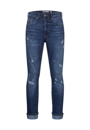 Jeans ajustados en denim azul oscuro, con parches desgastados y puños enrollados. Diseño clásico de cinco bolsillos con herrajes de latón.
