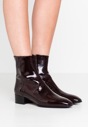 Stivali alla caviglia in pelle verniciata bordeaux con punta affusolata e tacco basso a blocco, caratterizzati da una finitura liscia e lucida e chiusura con zip laterale.