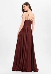 Bordeauxrode jurk van satijnen stof met een aansluitend lijfje en een vloeiende, geplooide rok. Voorzien van dunne spaghettibandjes en een ritssluiting aan de achterkant.