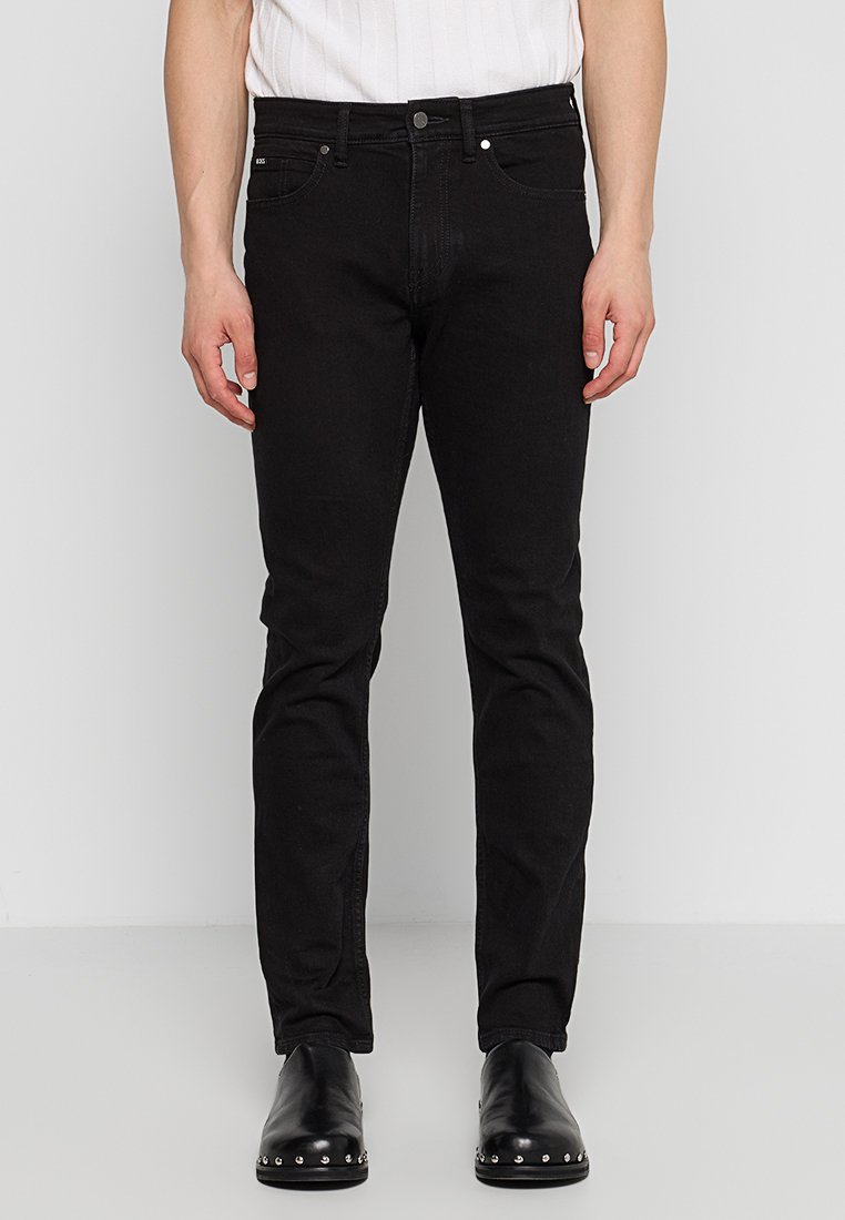 Jean slim noir en denim, avec un design classique à cinq poches, fermeture par bouton et légèrement extensible pour plus de confort.