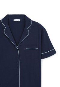 Camicetta da pigiama blu navy a maniche corte con piping bianco, dotata di colletto con scollatura a V e una piccola tasca sul petto con trim coordinato.
