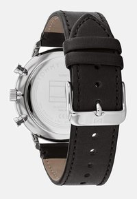 Orologio con cinturino in pelle nera, cassa in acciaio inossidabile, componenti in tono argento e funzione cronografica. Presenta un interno di colore crema e cuciture precise.