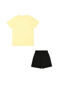 Camiseta amarilla de manga corta y pantalones cortos negros, con cuello redondo y cinturilla elástica, confeccionados con tela ligera para mayor comodidad.