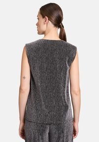 Top senza maniche di un grigio metallico scuro con una superficie texture e un leggero luccichio, caratterizzato da un taglio boxy e una parte posteriore dritta.