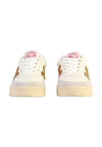 Zapatillas blancas con detalles de ante marrón, que presentan una puntera redonda, cordones planos y un parche de logo rosa en la lengüeta. Suela de goma texturizada.