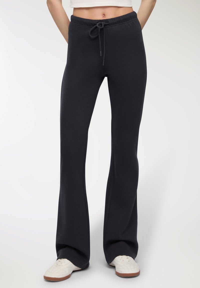 Czarne dzwony ze swobodnymi spodniami z miękkiego materiału, z elastycznym paskiem w talii i regulowanym sznurkiem, charakteryzujące się luźnym krojem aż do kostek.