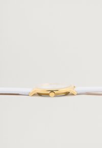 Ceas cu ton de aur, cu un cadran rotund și curea din piele albă. Dispune de o coroană, un cadran minimalist și o textură netedă.