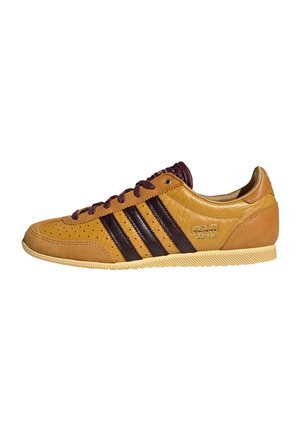 Zapatilla Adidas de piel marrón y beige tipo low-top con rayas marrón oscuro, perforaciones y suela texturizada, con la etiqueta "Adidas Japan" en el lateral.