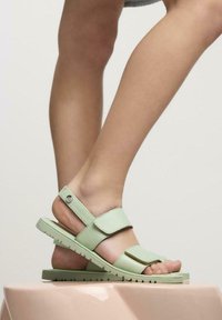 Sandalias verde claro con dos correas ajustables, suela plana y suela texturizada. Diseño de punta abierta con una plantilla acolchada.