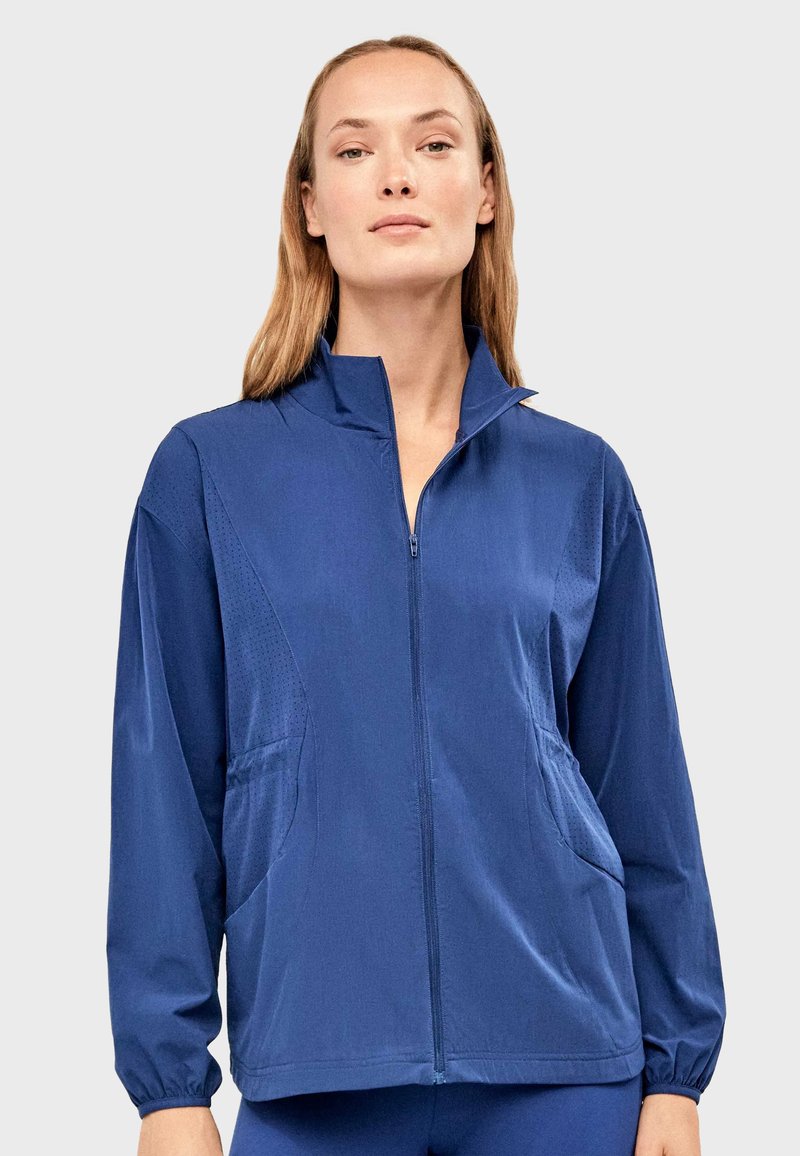 Marineblauw lichtgewicht jack met een hoge kraag, een volledige ritssluiting aan de voorkant, zijzakken en een subtiel gestructureerd patroon op de mouwen.