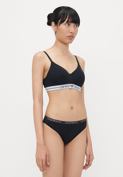 Black bra and bikini set with a soft texture. Bra features a v-shaped design with a logo band, while the bikini has a matching logo waistband.