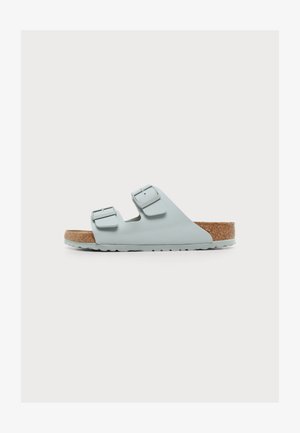 Sandale bleu clair à enfiler avec deux boucles réglables et une semelle en liège sur fond blanc.
