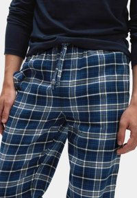 Pantalones de pijama a cuadros en azul y blanco, con cintura elástica y cordón, fabricados con un tejido suave y con un corte holgado.