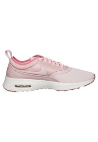 Baskets Nike rose clair avec semelle blanche, unité d'amorti Air, design à lacets et languette de traction au talon, vues de profil.