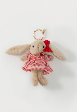 Porte-clés en peluche représentant un lapin beige portant une robe vichy rouge avec un nœud rouge sur l'oreille et un petit pendentif en forme de coccinelle sur un collier, sur fond blanc.