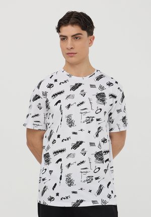 T-shirt bianco a maniche corte con un motivo astratto nero variegato. Realizzato in cotone con colletto a giro. Senza etichette o marchi visibili.