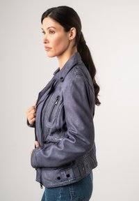 Leren motorjack in zacht, gedempt paars, met ritssluitingen voor zakken, een drukknoopkraag, decoratieve naden en een getailleerd silhouet.