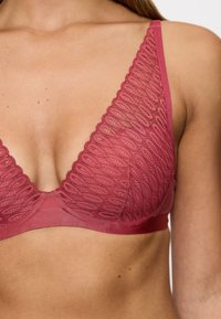Bralette triangular en rosa profundo con detalles de encaje, banda inferior de satén suave y patrones tejidos intrincados a lo largo de las copas. Clips en la parte posterior.