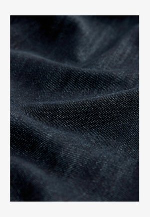 Ciemny denimu materiał o subtelnej teksturze, z gładką powierzchnią i lekkim połyskiem, przedstawiający złożone i drapowane wzory.