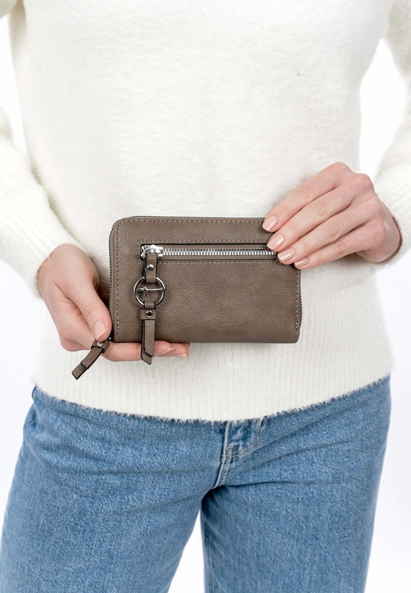 Brown leather wallet with a zippered compartment, circular accent hardware, and textured finish. Held against a light background.