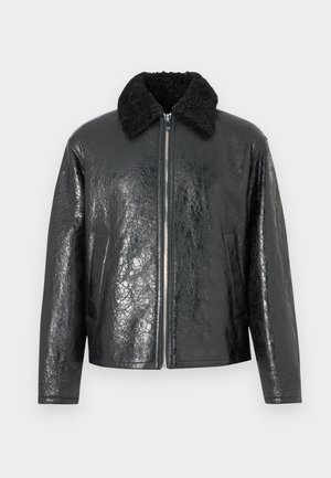 Black faux leather jacket with a shiny, textured finish. Features a black shearling collar and front zip closure. Two side pockets included.