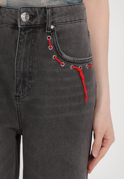 Gray denim jeans feature red laces threaded through metal grommets, adding texture and detail to the design at the front pocket area.