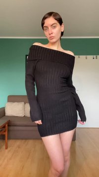 Vestito maglione nero con scollo a spalle scoperte, trama a coste, maniche lunghe e silhouette aderente, che termina a metà coscia.