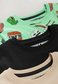 Drie T-shirts: de bovenste is mintgroen met cartoonafbeeldingen, de middelste is effen zwart, en de onderste is beige met een ribbelneklijn.