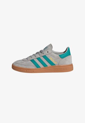 Grå semskede sneakers med tre turkise striper, polstret tunge og lys brun gummisåle med teksturdetaljer. Gullmerke på siden.