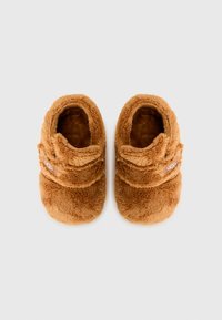 Brune, plysj sandaler med en myk tekstur, med en buet form og en stropp over toppen. UGG-logo på siden.