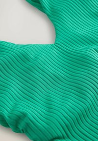 Detailný záber tyrkysovej látky s vystúpenou vlnitou rebrovanou textúrou, ktorá ukazuje jej trojrozmerný vzor a hladký povrch.