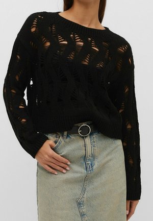 Un pull en tricot noir avec un design à mailles ouvertes, présentant des manches longues et un col rond, associé à une jupe en denim taille haute.