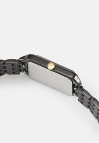 Svart klocka i rostfritt stål med rektangulärt urtavla, guld krona detaljer och texturerat armband. Baksidan har ingraverad text.