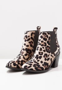 Botines de ante con estampado de leopardo, paneles laterales de elastano negro mate, punteras en punta y tacones de bloque, con un upper de tela texturizada.