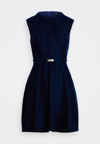 Námornícky bezrukávový šaty s plisovaným telom a rozšírenou sukňou, vyrobené z jemného zamatového materiálu; na páse sa nachádza strieborná pracka.