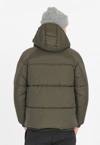 Olivengrøn pufferjakke med hætte, der har quiltede sektioner og elastiske manchetter. Overfladen ser glat og let blank ud.