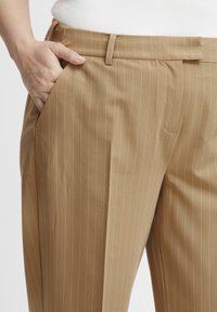 Khaki gestreepte broek van een gladde stof, met een zijzak, riemlussen en een getailleerde pasvorm.