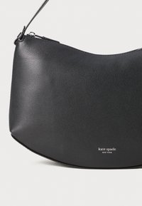 Borsa in pelle nera con forma semicircolare, texture liscia, chiusura con zip sulla parte superiore e branding sottile in bianco sul fondo.